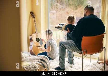 Père passant du temps libre avec des enfants jouant avec des instruments de musique à la maison Banque D'Images