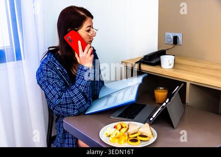 Femme télétravaillant à domicile et prenant son petit déjeuner Banque D'Images