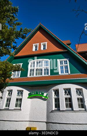 Maison traditionnelle verte et blanche avec toit rouge et de grandes fenêtres sous Un ciel bleu clair - la ville balnéaire de Świnoujście. Banque D'Images