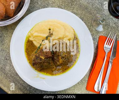 Il y a une portion de rôti de bœuf avec sauce moutarde sur l'assiette et le plat d'accompagnement de purée de pommes de terre Banque D'Images
