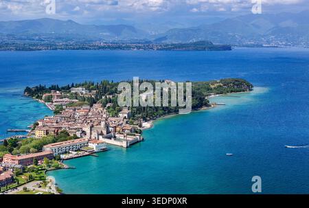 Vue aérienne de la péninsule historique de Sirmione et du château de Scaligero sur les rives du lac de Garde avec de l'eau turquoise et des montagnes à Sirmione, Lombar Banque D'Images