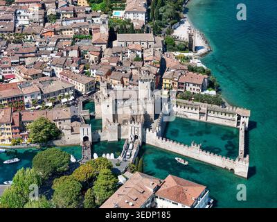 Vue aérienne du château de Scaliger et du centre-ville historique entouré par les eaux turquoises du lac de Garde à Sirmione, Lombardie, Italie. Banque D'Images