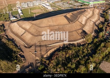 Brasov, Roumanie - 28 avril 2026 : vue aérienne d'un grand chantier de terrassement en terrasses avec des chemins de terre et des bâtiments industriels environnants UEDN Banque D'Images