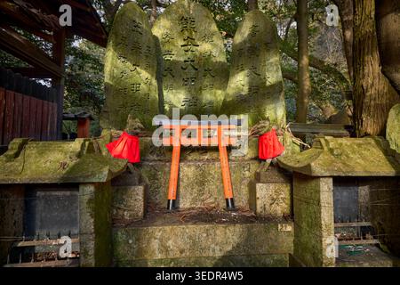 Statues de renard avec bavoirs rouges et portes torii miniatures vermillon au sanctuaire Fushimi Inari, le sanctuaire shinto de tête du kami Inari Okami à Kyoto, au Japon. Banque D'Images