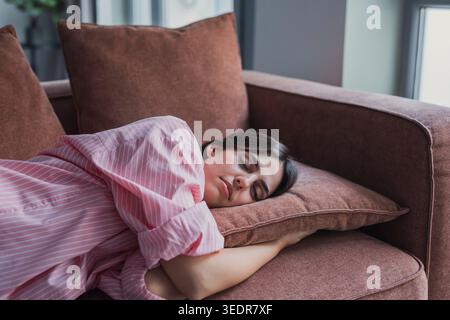 Malheureuse femme hispanique latine caucasienne allongée sur un canapé, souffrant de pensées négatives, s'ennuyant, passant le week-end seul à la maison. Stressée femme millénaire se sentant mal, concept de dépression. Banque D'Images