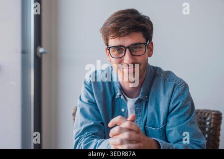 Un chef d'équipe de la génération y, barbe et lunettes, regarde la caméra lors d'une réunion virtuelle, organise un atelier en ligne et communique en toute confiance avec les employés par le biais d'un appel vidéo Banque D'Images