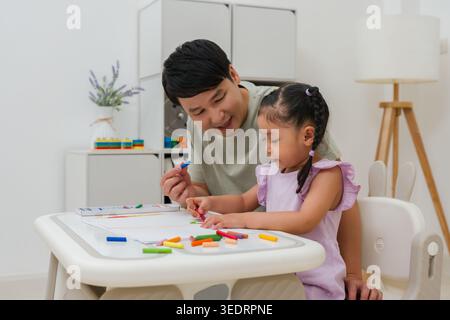 père et enfant fille dessin et peinture avec des pastels à l'huile colorés sur papier à la maison Banque D'Images
