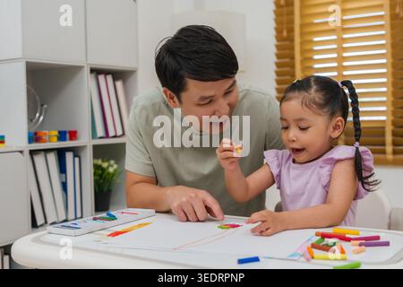 père et enfant fille dessin et peinture avec des pastels à l'huile colorés sur papier à la maison Banque D'Images