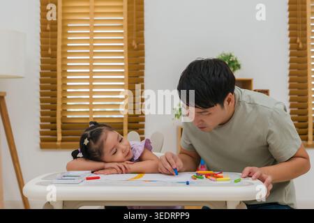père et enfant fille dessin et peinture avec des pastels à l'huile colorés sur papier à la maison Banque D'Images