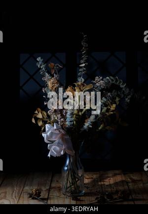 Bouquet de fleurs séchées avec eucalyptus et ruban dans un vase en verre Banque D'Images