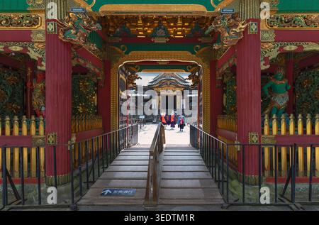 L'architecture du sanctuaire japonais richement décorée encadre une passerelle avec les visiteurs au loin dans une composition symétrique. Banque D'Images