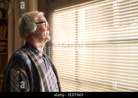 Homme senior portant des écouteurs et se relaxant à la maison pour le bien-être Banque D'Images