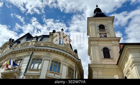 Vue urbaine de l'hôtel de ville de Sibiu et du clocher de l'église catholique de la Sainte-Trinité surplombant la place historique Piata Mare. Banque D'Images