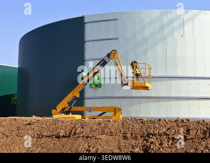 Cueilleur de cerises jaunes travaillant sur la construction d'un grand réservoir industriel dans l'industrie pétrolière. Banque D'Images