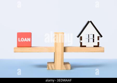 Blocs en bois avec le mot prêt et maisons en bois sur une balance en bois. Évaluation des prêts personnels. Voiture, maison, concept de prêt d'argent personnel. Banque D'Images