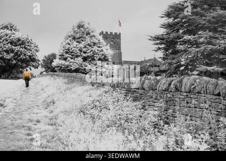 Mur de pierre traditionnel et église sur la droite de passage à Guiting Power, en Angleterre dispose d'un clocher normand. Banque D'Images