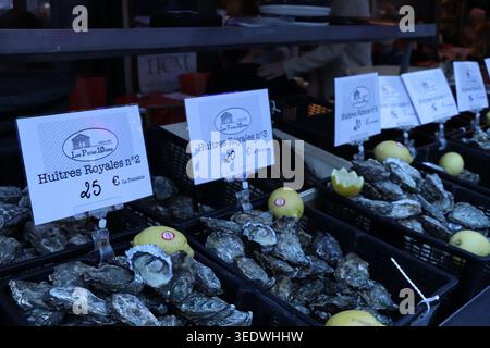 Une gamme de baies biologiques fraîches, raisins et agrumes dans des cagoules colorées et des caisses exposées à la vente sur un marché français en plein air animé. Banque D'Images