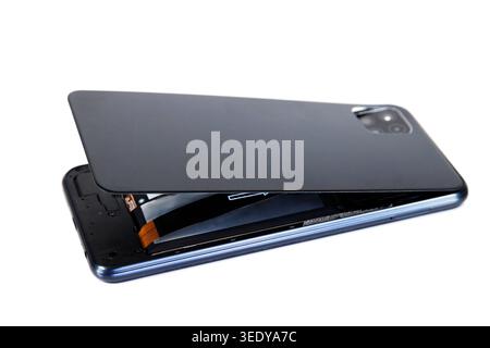 Smartphone avec un couvercle arrière ouvert révélant l'électronique interne, la carte électronique et la batterie, symbolisant la réparation et l'entretien Banque D'Images