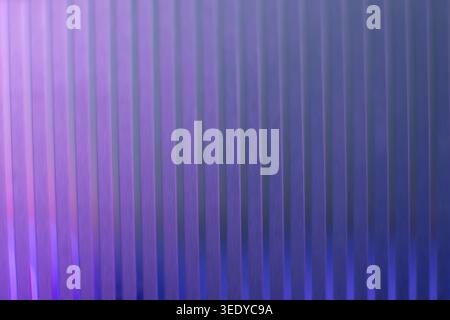 Éclairage au néon violet vif et bleu profond sur une texture ondulée verticale Banque D'Images
