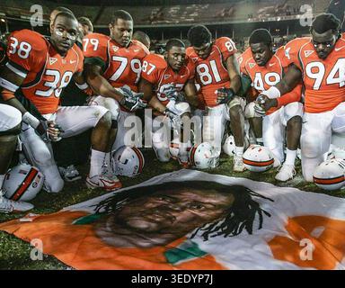 Miami, États-Unis. 07 mai 2026. Des joueurs de football de l'Université de Miami, dont Rashaun Jones (38) à gauche, se tiennent la main à mi-terrain devant une fresque de son coéquipier Bryan Pata au stade Orange Bowl de Miami le 23 novembre 2006. Jones a été arrêté le 19 août 2021, en relation avec la fusillade mortelle de Pata. (Photo par Al Diaz/Miami Herald/TNS/Sipa USA) crédit : Sipa USA/Alamy Live News Banque D'Images