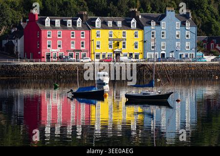 Vue sur les maisons colorées emblématiques le long du front de mer avec des bateaux amarrés dans le port et des reflets vibrants sur l'eau Tobermory, Écosse, Unit Banque D'Images