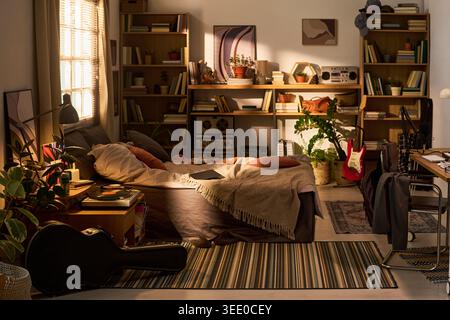 Grand plan de studio de chambre élégant avec lit, bureau, étagères, guitare, tourne-disque, plantes, créant un concept créatif de vie à la maison. Idéal pour l'intérieur, la location, le marketing lifestyle Banque D'Images