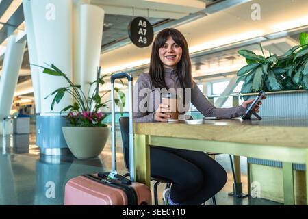 Femme voyageant se relaxant à l'aéroport avec du café et de la tablette Banque D'Images