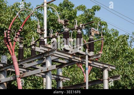 Gros plan d'isolateurs électriques en céramique montés sur un poteau en bois avec des lignes électriques aériennes dans un cadre extérieur naturel. Banque D'Images
