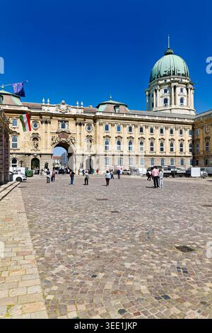Les visiteurs se rassemblent autour du château de Buda à Budapest. Le soleil brille brillamment tandis que les gens explorent le site historique et prennent des photos. Banque D'Images