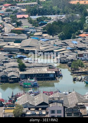 La vue aérienne capture la communauté tranquille de village de pêcheurs rustique avec une structure de maison en bois sur pilotis au-dessus de l'eau reflétant le style de vie résilient de Banque D'Images