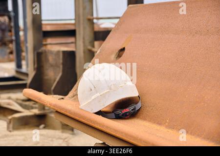 Santé et sécurité : risques liés à la construction et au lieu de travail casque blanc sur palplanche rouillée sur le chantier de construction Banque D'Images