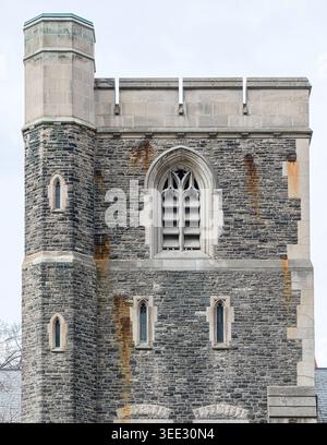 Tour en pierre avec parapet crénelé, tourelle étroite, fenêtre voûtée gothique, ouvertures fendues et maçonnerie altérée avec des stries de rouille. Banque D'Images