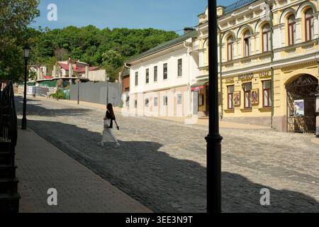 Une femme marche gracieusement le long d'une rue pavée pittoresque, prélassant dans la lumière du soleil. Andriyivskyy Descent, Kiev, Ukraine, 8 mai 2026 Banque D'Images