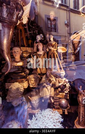 Une vue rapprochée d'une vitrine de magasin à Florence, en Italie, remplie d'un éventail d'objets anciens et vintage. L'affichage comprend divers mannequins, bustes Banque D'Images
