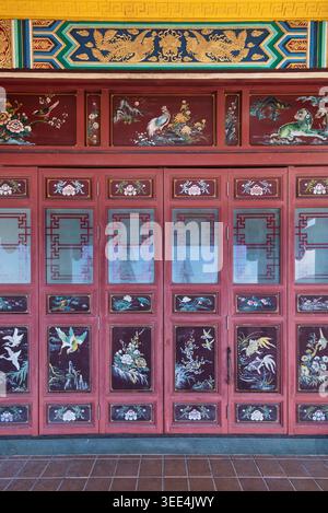 Terrasse au temple Chin Swee Caves, Genting Highlands, Pahang, Malaisie. Art chinois traditionnel vibrant avec des phoenixes dorés, des oiseaux et des motifs floraux sur des panneaux en bois rouge ornés Banque D'Images