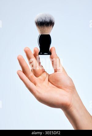 Brosse, studio et main de l'homme avec soin de la peau, cosmétique et nettoyage pour la routine ou le rasage sur fond bleu. Paume et produit avec outil souple ou Banque D'Images