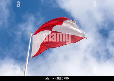 Drapeau national de Malte agitant contre le ciel bleu avec des nuages blancs. Drapeau maltais rouge et blanc sur mât de drapeau à l'extérieur, symbole de l'identité maltaise, patriotisme, Banque D'Images