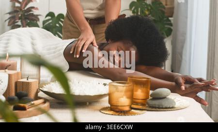 Séance de massage relaxante au spa avec femme souriante recevant un traitement d'aromathérapie dans la confortable salle de bien-être Banque D'Images