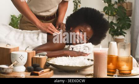 Femme souriante recevant un massage relaxant du dos au Spa avec bougies et aromathérapie Banque D'Images