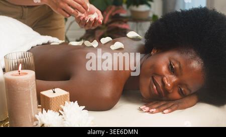 Massage relaxant au spa avec pétales de roses et bougies - femme bénéficiant d'un traitement d'aromathérapie Banque D'Images