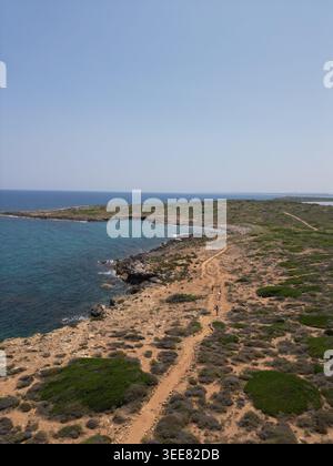 Vue aérienne de la plage de Calamosche avec une côte rocheuse, eau turquoise, et les gens marchant le long d'un chemin de terre à Noto, Sicile, Italie. Banque D'Images