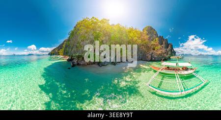 Entalula Beach à El Nido, Philippines, falaises de calcaire, végétation tropicale vibrante et bateaux traditionnels flottant sur des eaux cristallines Banque D'Images