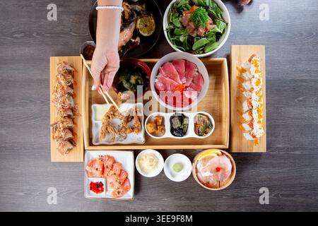 Vue de dessus sur un plateau de fruits de mer d'un restaurant japonais, avec sushis, petits pains, nigiri et hors-d'œuvre frits. Banque D'Images
