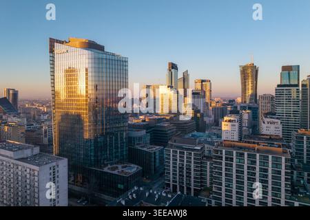 Varsovie, Pologne - 07 mars 2026 : vue aérienne de gratte-ciel modernes avec la lumière dorée du soleil se reflétant sur les façades en verre sous un ciel bleu clair de la ville Banque D'Images