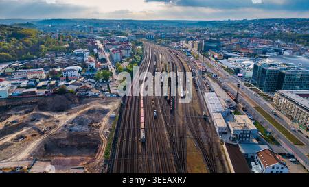 Prague, Tchéquie - 21 avril 2026 : vue aérienne d'une grande gare de triage avec des trains de marchandises sur plusieurs voies entourées de bâtiments urbains et de verdure Banque D'Images