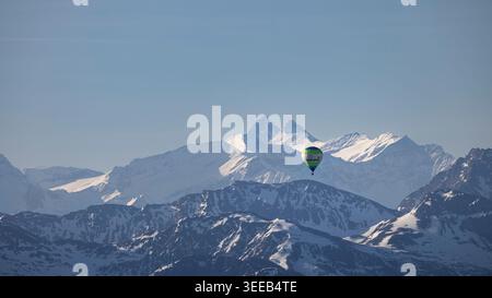 Montgolfière volant au-dessus de la chaîne de montagnes alpines enneigées en Autriche Banque D'Images