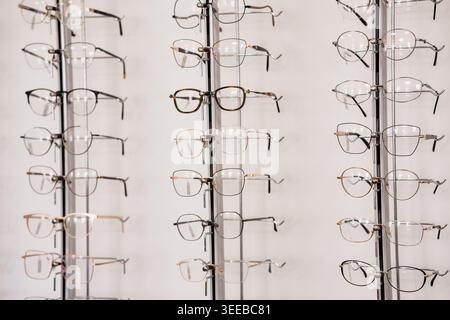 Assortiment moderne de lunettes de vue de différents styles présentés sur des supports verticaux dans la salle d'exposition lumineuse de la clinique d'optométrie Banque D'Images