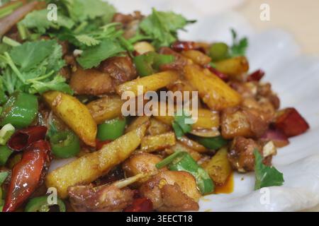 Poulet sec (gān guō jī) également appelé poulet chaud cuit avec des pommes de terre, du piment, de l'ail et du poulet servi dans un restaurant à Emeishan Banque D'Images