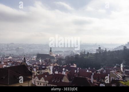 Vue sur les toits rouges historiques et les flèches de l'église du quartier de Mala Strana sous un ciel brumeux matinal à Prague, Prague, Tchéquie. Banque D'Images