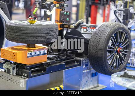 Gros plan des roues de voiture de manutention de machine de changement de pneu automatisée dans le garage de réparation automobile moderne, le service de pneus professionnel et l'équipement d'entretien Banque D'Images